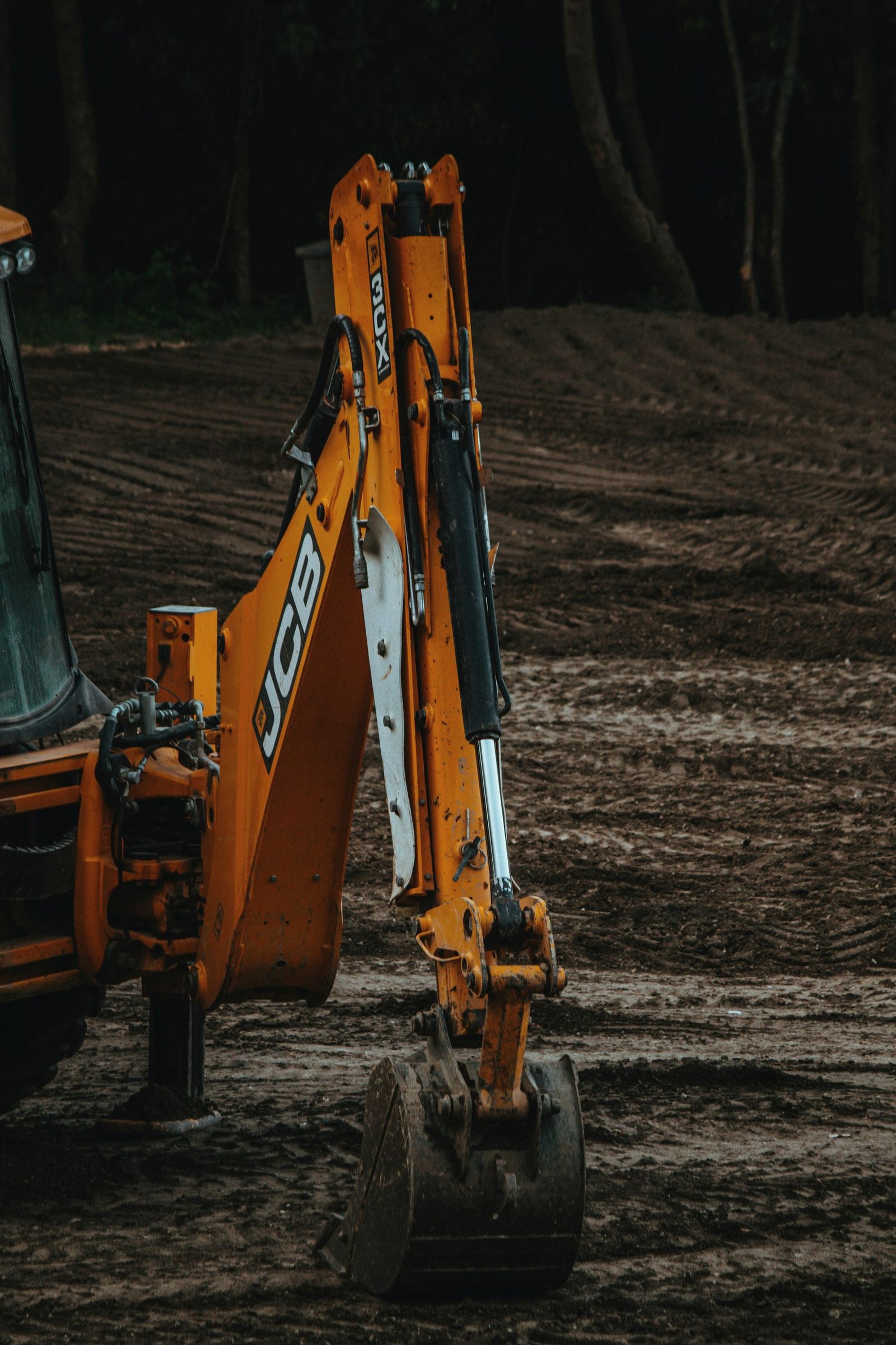 An excavator arm and bucket working over broken ground.