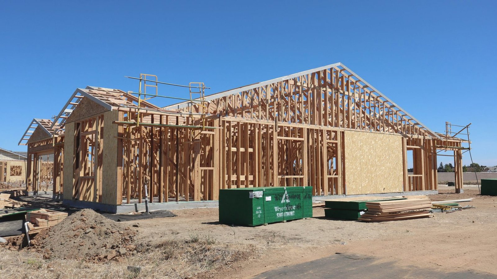 A timber framed house under construction against a blue sky.